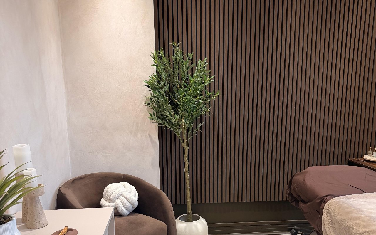 Treatment bed beside the warm wooden slatted wall at The Eye Stylist